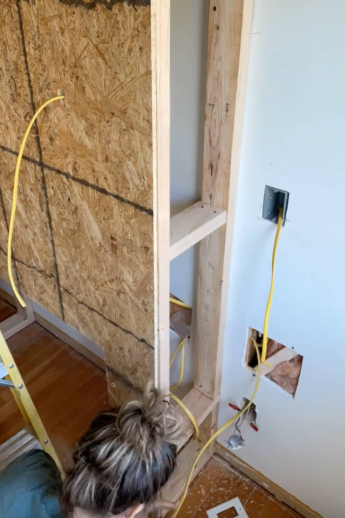 Running electrical wire for an outlet in a fireplace mantel.